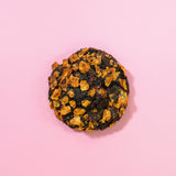 Caramel Cornflake New York Cookie with dark chocolate and toasted caramel cornflake topping on pink background by Crumbs & Doilies
